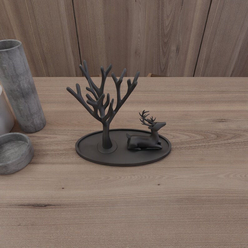 May include: Black metal ring holder shaped like a tree with a deer figurine on a black oval base.