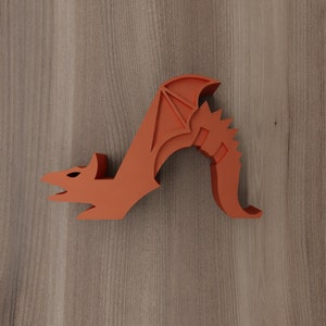 May include: Orange dragon figurine with wings outstretched and a curled tail. The dragon is made of a smooth, solid material and has a stylised design.