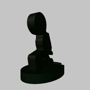 May include: Black ceramic figurine of a person sitting with their legs crossed. The figurine is stylised and abstract.