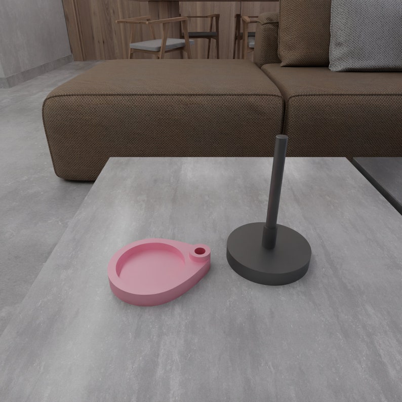 May include: A pink and black ceramic tray set with a round, shallow dish and a tall, cylindrical stand. The tray set is on a gray, textured surface.