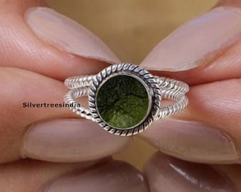May include: A silver ring with a twisted band and a round green stone set in a silver bezel.