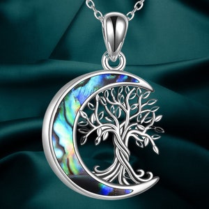 May include: A silver necklace with a crescent moon pendant featuring a tree of life design. The moon is made of iridescent abalone shell with blue, green, and gold hues.