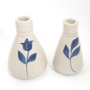 May include: Two ceramic vases with blue floral designs. The larger vase has a tulip design and the smaller vase has a leaf design.