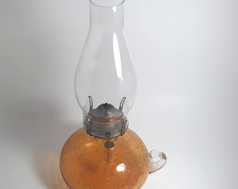 Lámpara de aceite vintage tipo huracán con cristal craquelado y asa, color ámbar y cristal transparente.