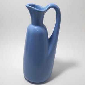 Puede incluir: Una taza de cerámica blanca con asa negra y el texto "But First, Coffee" en negrita negra. La taza está sobre un fondo borroso. La taza mide aproximadamente 10 cm de altura.