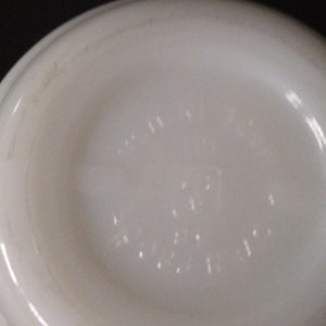 May include: White ceramic bowl with a raised rim and a small, embossed logo on the bottom. The logo reads "Made in USA" and "Pyrex".