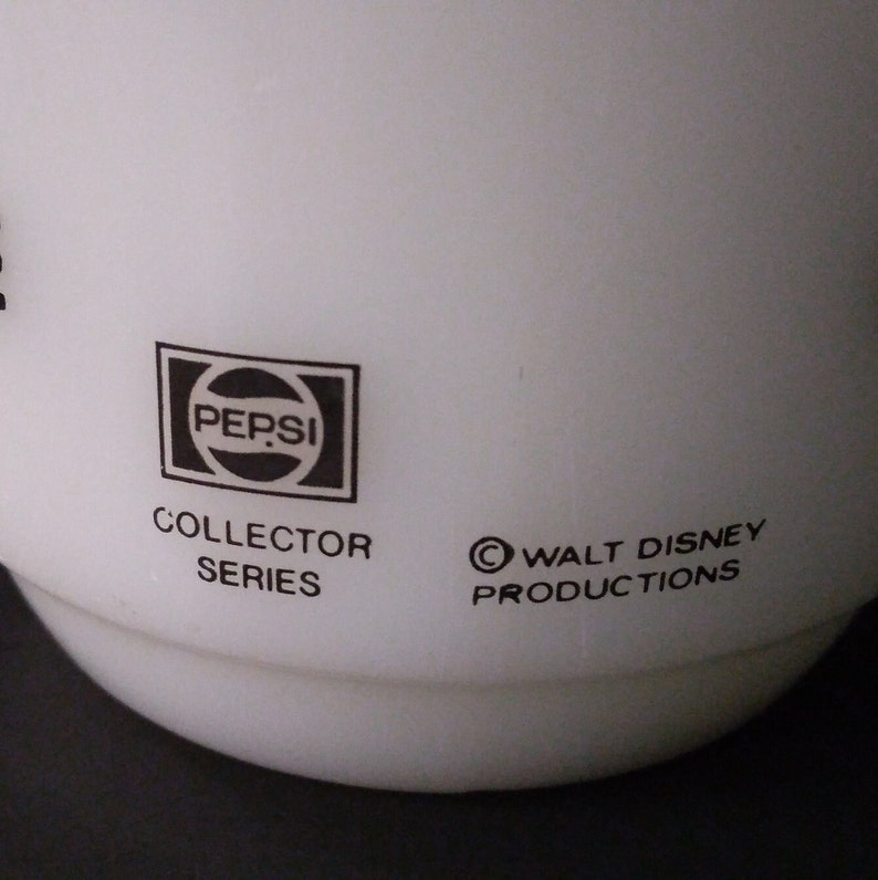 May include: White ceramic mug with a black Pepsi logo, "Collector Series" and "&copy; Walt Disney Productions" text.