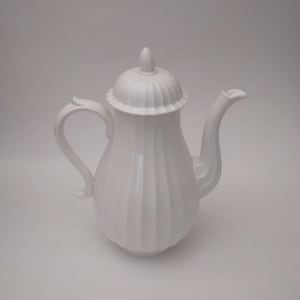 Puede incluir: Tetera de cerámica blanca con un diseño acanalado y una tapa. La tetera tiene un asa y un pico.