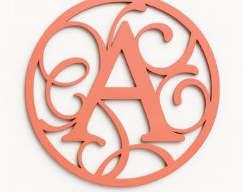 May include: A coral-coloured wooden monogram letter "A" inside a circular frame. The design includes elegant, swirling flourishes around the letter, creating a decorative wall art piece. The letter is centrally positioned within the circle.