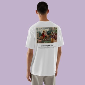Könnte beinhalten: Ein weißes kurzärmeliges T-Shirt mit einer rechteckigen Grafik auf der Rückseite. Der Druck zeigt eine historische Szene mit Figuren auf einem Löwen, begleitet von dem Text Agamani-vijaya - 1878 und einem beschreibenden Absatz in Schwarz.