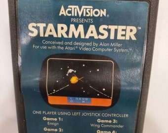 May include: A blue and black Atari video game cartridge for StarMaster, a game conceived and designed by Alan Miller. The cartridge features a screenshot of the game with a spaceship and a starfield. The text "ACTIVISION PRESENTS STARMASTER" is printed on the front of the cartridge.