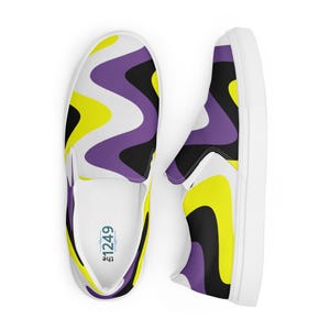 May include: Pair of slip-on sneakers with a white sole and a wavy pattern in yellow, purple, and black. The interior of one shoe displays the text "the 1249". The shoes are designed for casual wear.