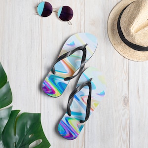 May include: A pair of blue and white flip flops with a colourful abstract design. The flip flops have black straps.