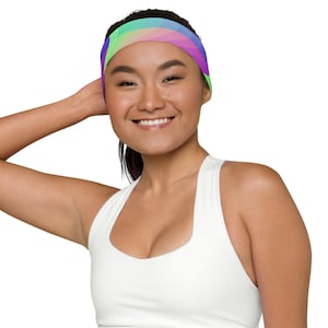 May include: A woman wearing a white tank top with a colourful headband. The headband has a geometric pattern with shades of pink, purple, green, and blue.