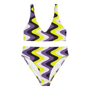 Könnte beinhalten: Ein Badeanzug in Lila, Gelb und Schwarz mit einem wellenförmigen Muster. Das Oberteil ist im Halstert-Stil und das Unterteil ist hoch tailliert.