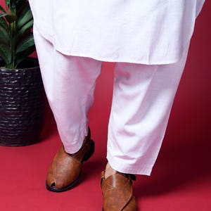 May include: A pair of brown leather sandals with a criss-cross strap design. The sandals have a pointed toe and a closed heel.