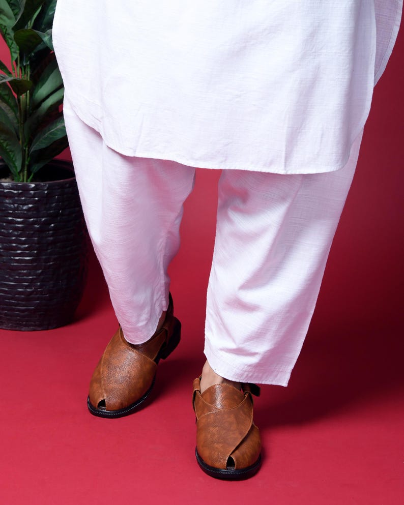 May include: A pair of brown leather sandals with a criss-cross strap design. The sandals have a pointed toe and a closed heel.