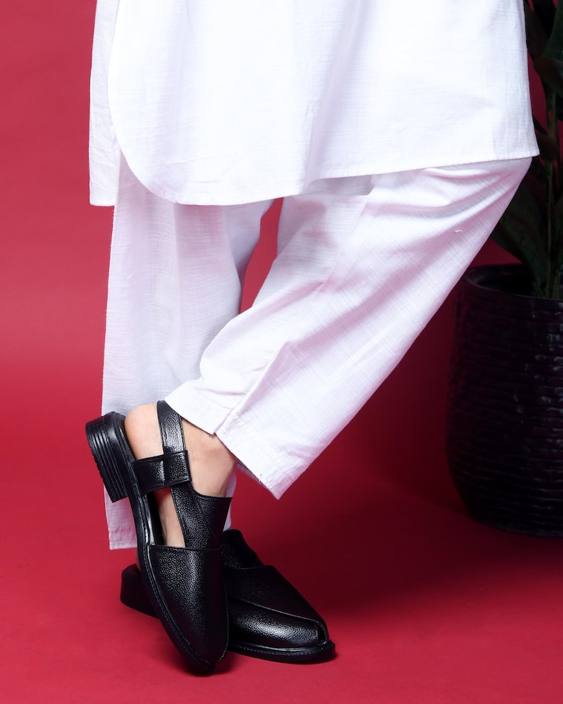 May include: A pair of black leather sandals with an open toe and ankle strap. The sandals have a pointed toe and a low heel.