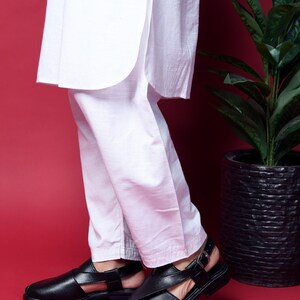 May include: A pair of black leather sandals with a buckle closure. The sandals have a strap across the top of the foot and an ankle strap.