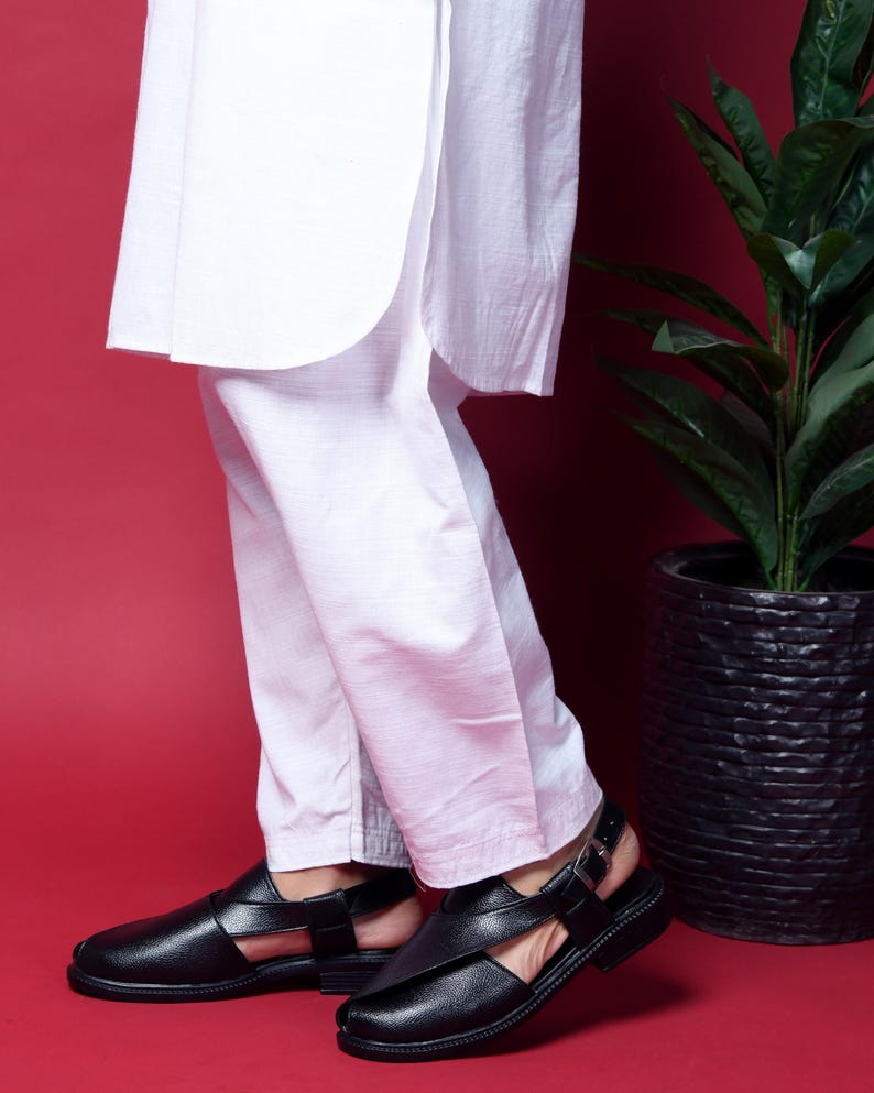 May include: A pair of black leather sandals with a buckle closure. The sandals have a strap across the top of the foot and an ankle strap.