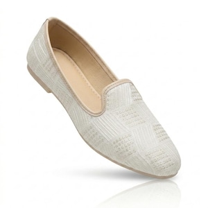 May include: Off-white slip-on shoe with a textured, geometric pattern. The shoe has a rounded toe and a low heel. The interior is a light beige colour, and the trim is a matching beige. The shoe is designed for casual wear.