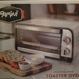 May include: A Parini stainless steel toaster oven with a glass door and two control knobs on the right side. The packaging features the brand name Parini, the text stainless steel TOASTER OVEN, and an illustration of bread, butter, and jam.