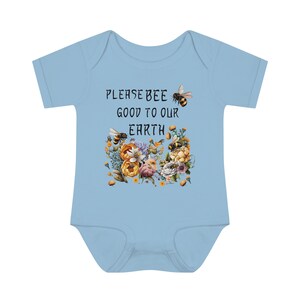 May include: Light blue baby onesie with short sleeves featuring a floral design with bees and the text "Please bee good to our Earth".