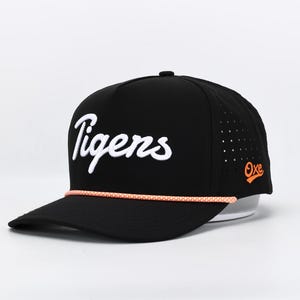 May include: Black baseball cap with the word "Tigers" in white script across the front. The cap has a curved brim, a perforated side panel, and an orange rope detail. The logo "Oxe" is on the side.