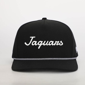 May include: Black baseball cap with a white rope trim and the word "Jaguars" written in white cursive lettering.