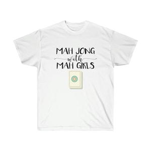 May include: White t-shirt with black text that reads "Mah Jong with Mah Girls" and a white mah jong tile with a green circle and a yellow dot in the center.