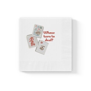 May include: White paper napkin with a red and brown illustration of three mahjong tiles and the text "Whose turn to deal?"