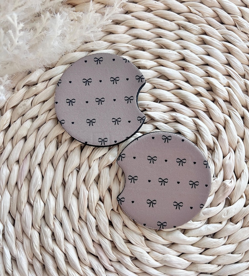May include: Two brown car coasters with a black bow and white dot pattern.