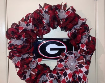 May include: A red, black, and white wreath with a black and white checkered ribbon and a football design. The wreath has a metal sign with a black and white "G" on it.