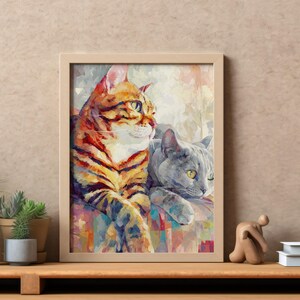 Puede incluir: Impresi&oacute;n art&iacute;stica enmarcada con dos gatos. Uno tiene rayas naranjas y negras, el otro es gris. La obra de arte est&aacute; en un estilo pict&oacute;rico colorido, con un marco de madera clara. Los gatos descansan sobre una superficie estampada.