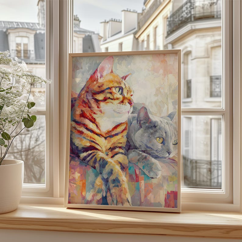 Puede incluir: Impresi&oacute;n art&iacute;stica enmarcada con dos gatos. Uno tiene rayas naranjas y marrones, el otro es gris. La obra de arte se exhibe en un alf&eacute;izar con vistas a un edificio de estilo europeo.