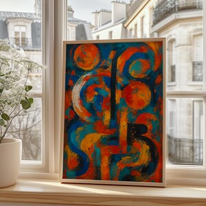 Puede incluir: Impresión artística abstracta en un marco de madera. La obra presenta una vibrante mezcla de colores, incluyendo naranja, azul y amarillo. El diseño incluye formas circulares y lineales, creando una composición dinámica. El arte enmarcado se exhibe en un alféizar.