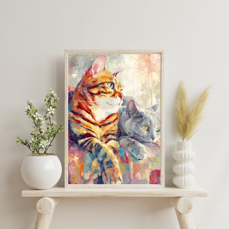 Puede incluir: Una impresi&oacute;n art&iacute;stica enmarcada con dos gatos. Uno tiene rayas naranjas y negras, el otro es gris. La obra de arte tiene un estilo abstracto y colorido, con un marco de madera clara. Los gatos est&aacute;n tumbados, uno mirando hacia un lado.