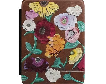 May include: A brown tablet case featuring a colorful floral design. The flowers include yellow, pink, red, and white blooms with green leaves. The case has a black spine and a textured surface.