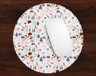 May include: A round white mousepad with a colorful pattern of various symbols, including hearts, stars, musical notes, and the number 13. The mousepad is on a wooden surface.