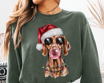 May include: Green long-sleeve sweatshirt with a dog wearing sunglasses and a Santa hat, blowing a bubblegum bubble. The dog is decorated with Christmas lights. The word "HEMP" is printed at the bottom of the image.