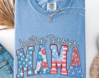 May include: A blue t-shirt with a distressed denim look. The shirt features a graphic of the words "boston terrier mama" in white with a red, white, and blue American flag design.