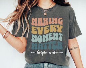 May include: A dark gray t-shirt with the text "Making Every Moment Matter - hospice nurse" in colorful retro font.