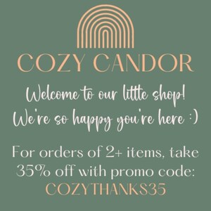 May include: A green background with a peach-colored rainbow graphic and the text "COZY CANDOR" in white. The text "Welcome to our little shop! We're so happy you're here :)" is also in white. The text "For orders of 2+ items, take 35% off with promo code: COZYTHANKS35" is in white.