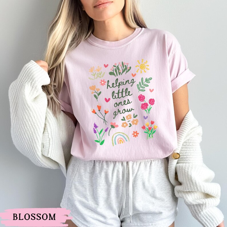 May include: A pink t-shirt with a floral design and the text "helping little ones grow".