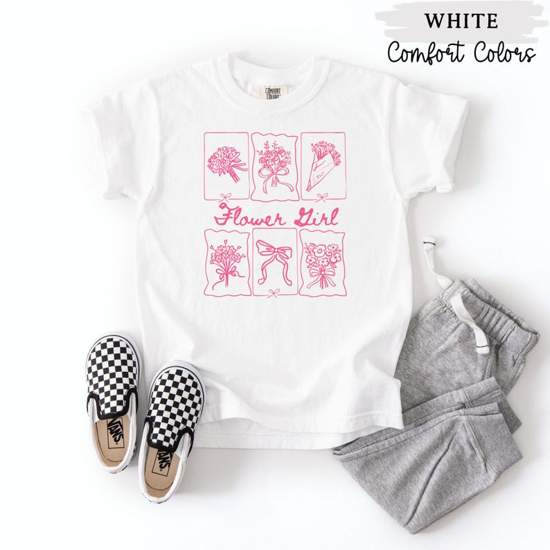 May include: White t-shirt with a pink floral design and the words "Flower Girl". The shirt is paired with gray sweatpants and black and white checkered slip-on shoes. The words "WHITE" and "Comfort Colors" are printed at the top.
