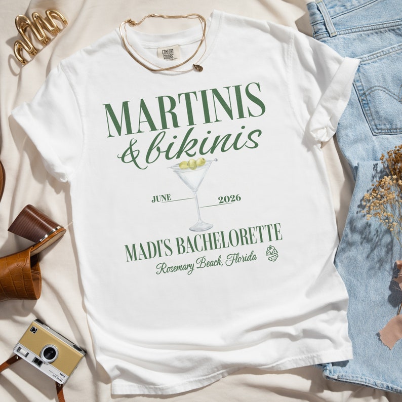 May include: White t-shirt with green text that reads "Martinis & bikinis" with a martini glass illustration and the text "June 2026 Madi's Bachelorette Rosemary Beach, Florida".