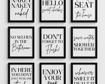 May include: Nine framed bathroom art prints with black frames and white backgrounds. Each print features black text with humorous phrases like "Nakey Naked Naked" and "Enjoy Your Poop".
