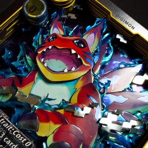 May include: A vibrant Digimon card with a 3D effect, showcasing a detailed illustration of a creature in red, blue, and yellow. The card displays the word "Digimon" and includes game tokens. The design has layered elements.