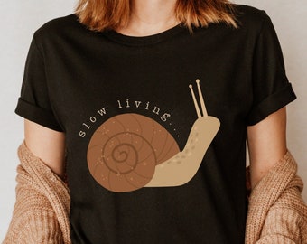May include: A black t-shirt with a brown snail graphic and the text "slow living..." printed in white.