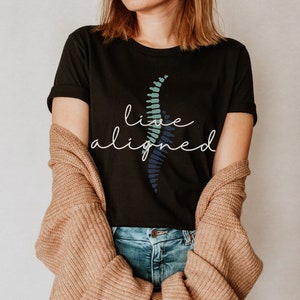 May include: A black t-shirt with a blue and green graphic of a spine and the text "live aligned" in white.